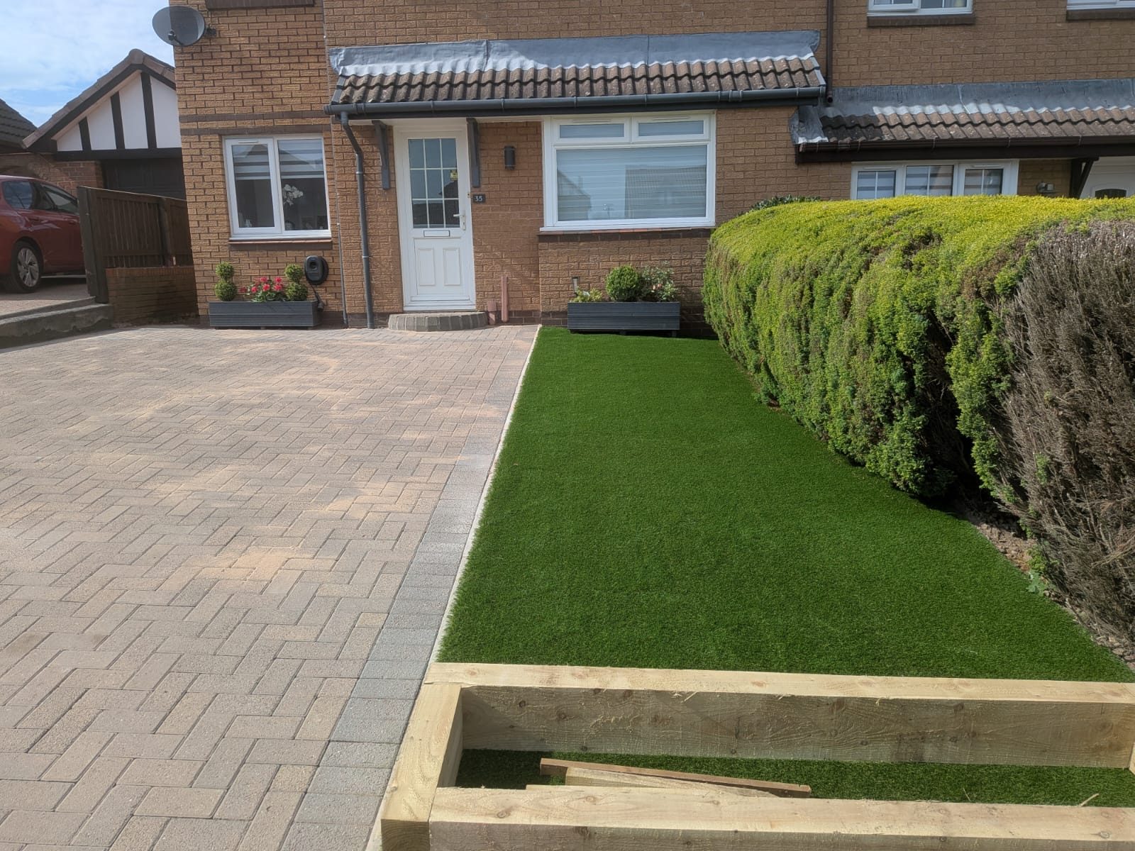 Artificial grass strip alongside a block-paved driveway